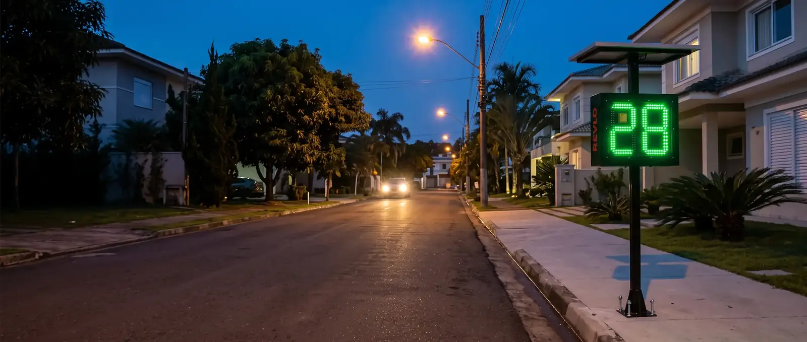 Lombada educativa Revlo em rua residencial ao entardecer, mostrando 28 para o carro que se aproxima
